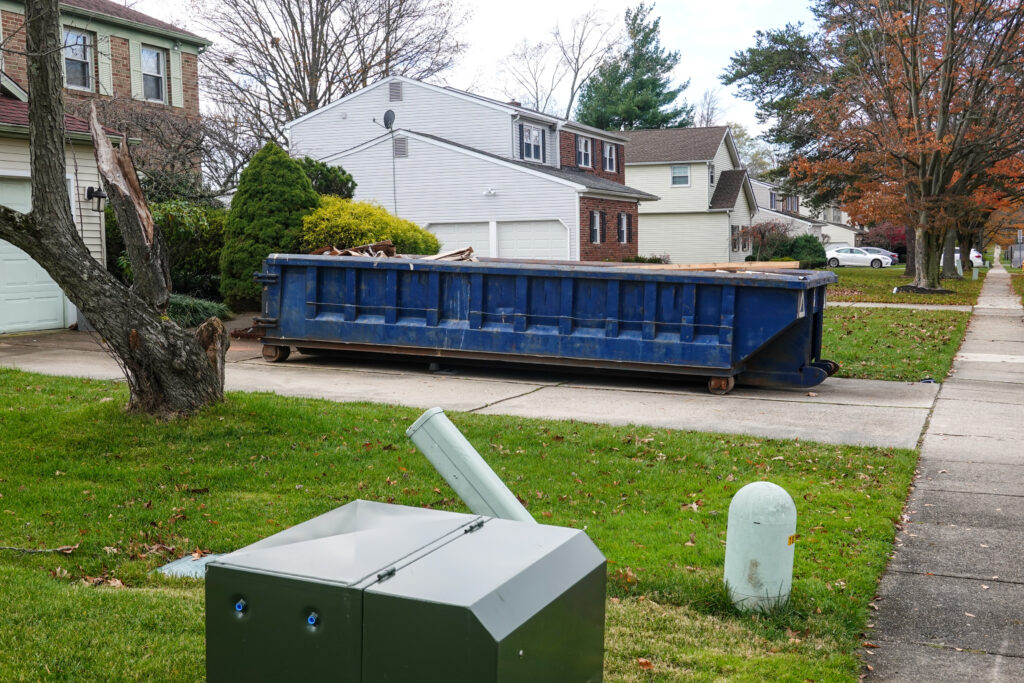 long blue dumpster full of wood and other debris in the driveway in front of a house in the Minneapolis, Minnesota suburbs